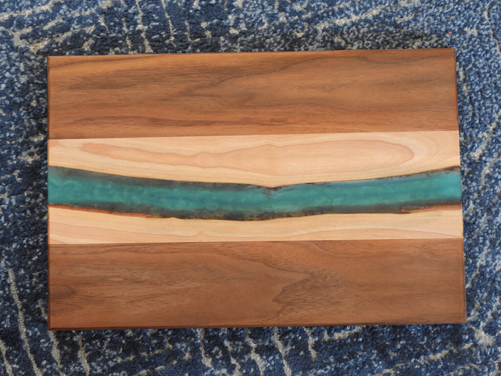 A wood cutting board with epoxy river inside