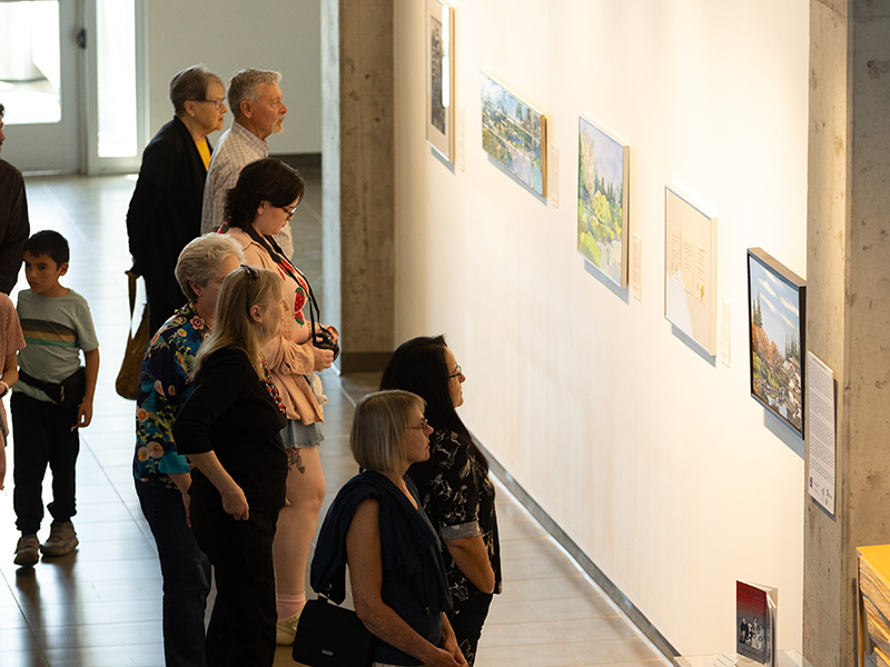Visitors look at artworks on the wall in the Passage Gallery at Casa