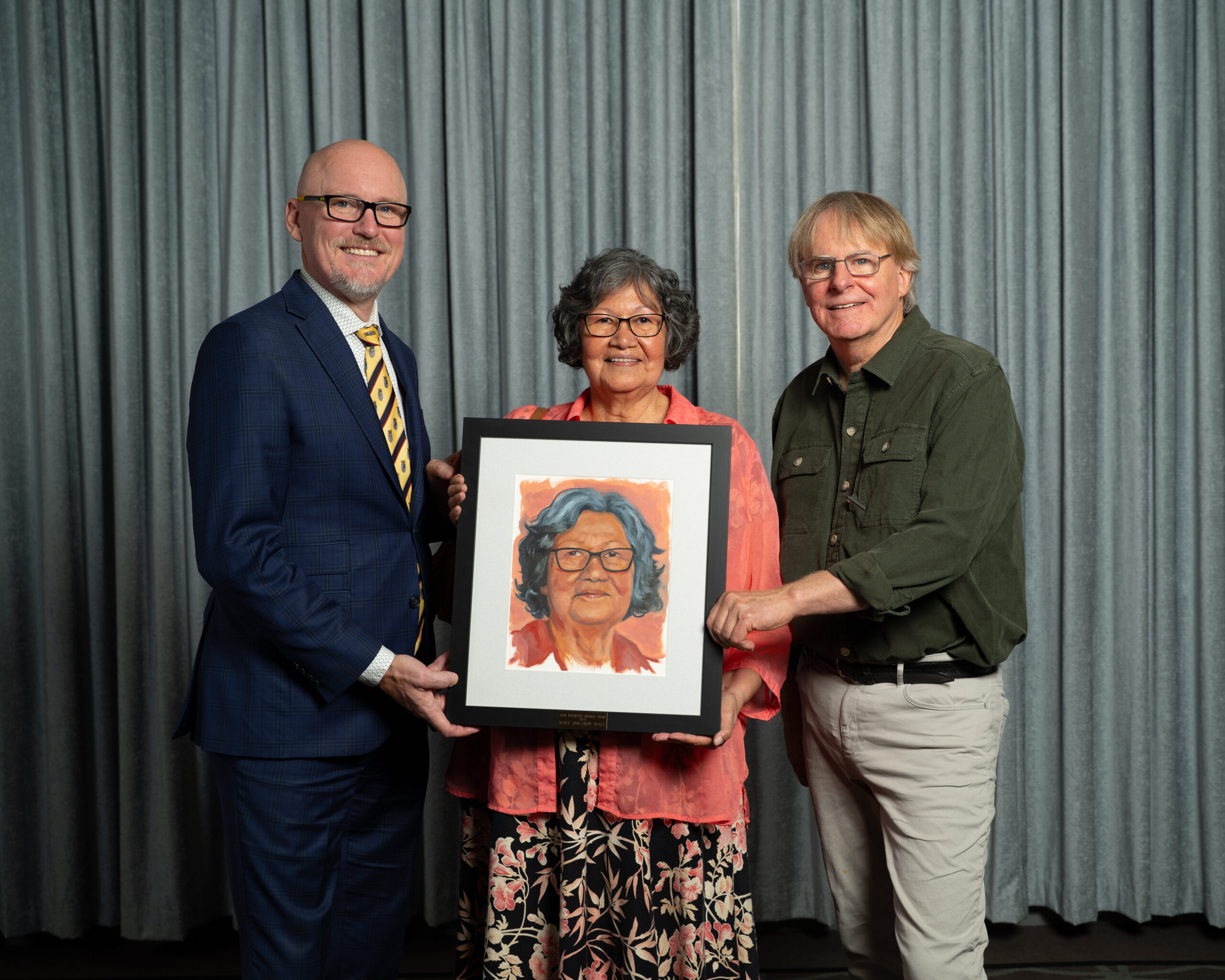 Joan Waterfield Memorial Recipient stands holding her commissioned portrait with Mayor Blaine Hyggen and AAC President Jon Oxley 